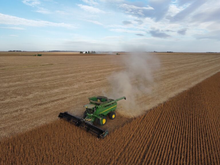 Combine harvesting soybeans in an eastern Iowa field, seen from a drone